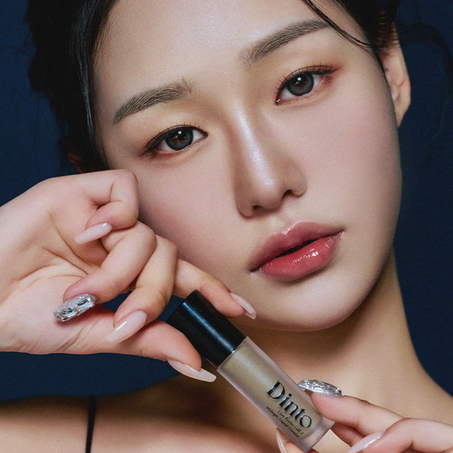 DINTO Midnight Liquid Contour 2 Types, produit de la marque DINTO sur une peau maquillée; visage féminin, éclairage studio bleu.