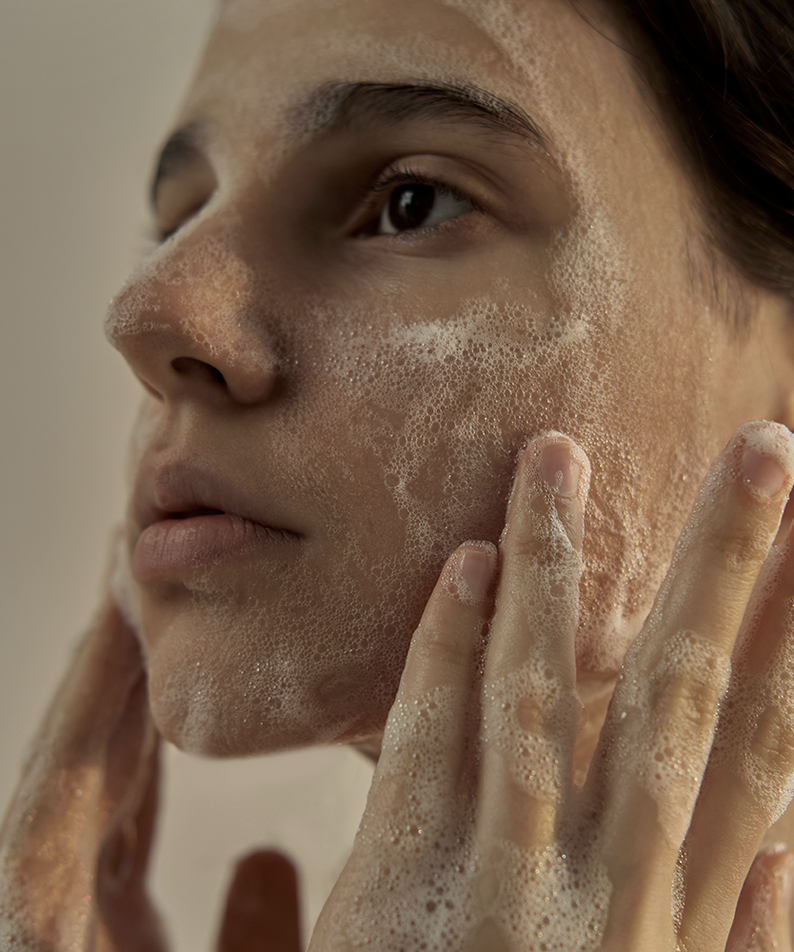 Jeune femme appliquant du savon DONGGUBAT Field Dream Soap Basil sur le visage, améliore la peau au naturel.