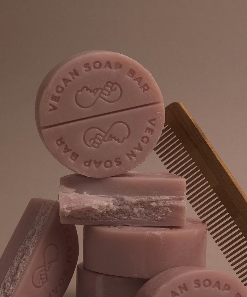 DONGGUBAT Vegan Shampoo Bar Dongbaek, savon végétalien rond rose avec peigne en arrière-plan, soin capillaire naturel.