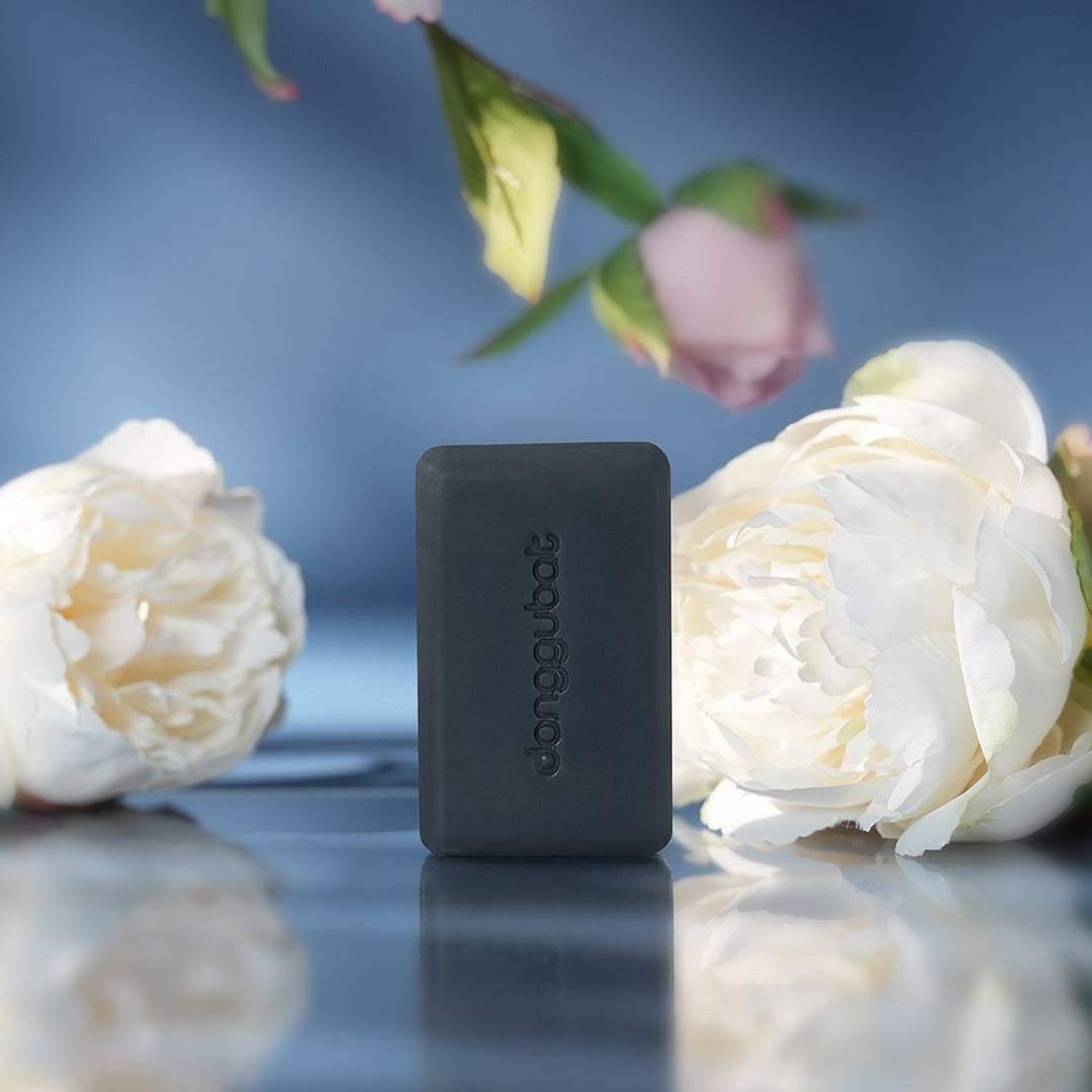 DONGGUBAT Field Blooming Perfume Shampoo Bar Repair 80g, savon shampoing noir entre fleurs blanches sur fond bleu