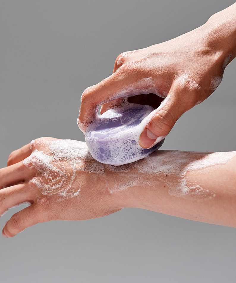 Décris l'image en français : DONGGUBAT Field Correct Cleansing Soap Collagen de la marque, mousse sur les mains sous douche.
