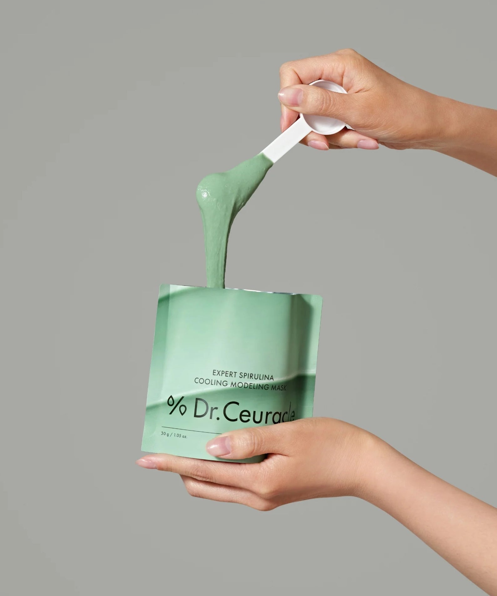 Application du DR.CEURACLE Expert Spirulina Cooling Modeling Mask 30g avec spatule, masque vert rafraîchissant en préparation.