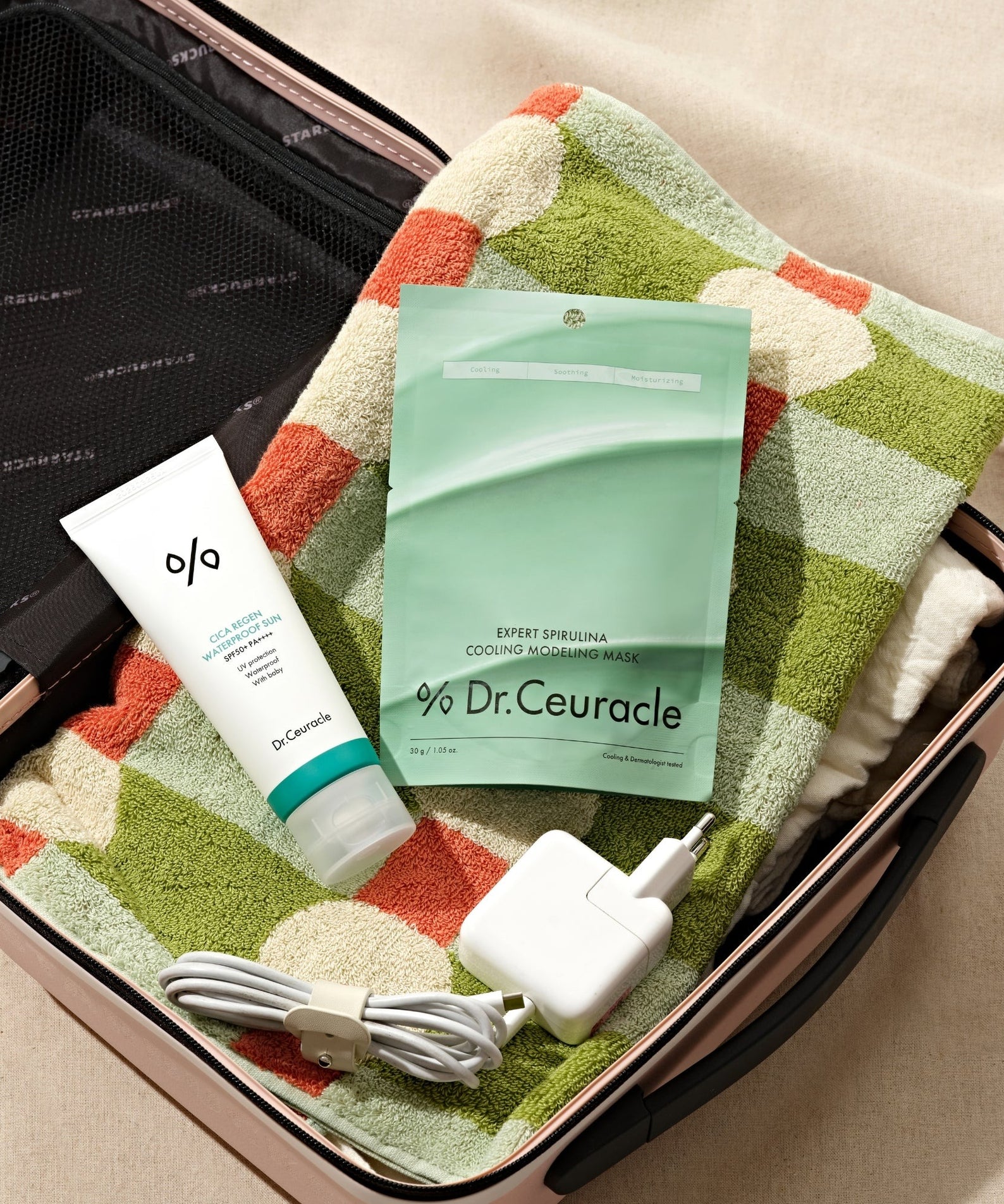 DR.CEURACLE Expert Spirulina Cooling Modeling Mask 30g sur une serviette colorée dans une valise, avec un chargeur et un tube.