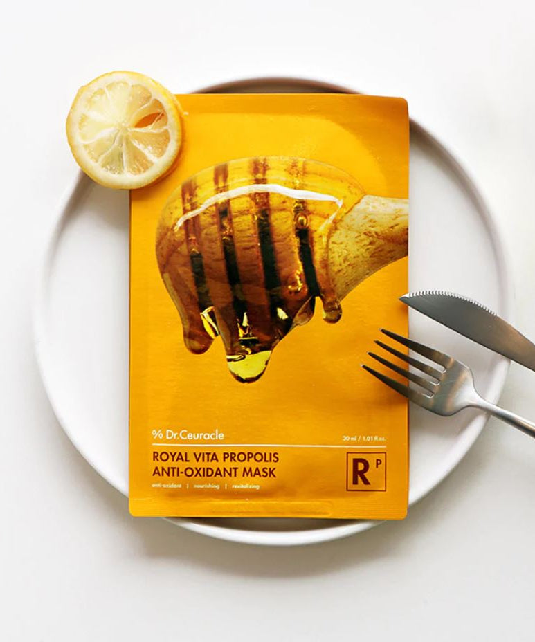 Masque DR.CEURACLE Royal Vita Propolis Glow (10EA) posé sur une assiette avec une tranche de citron pour soin de la peau éclatante.