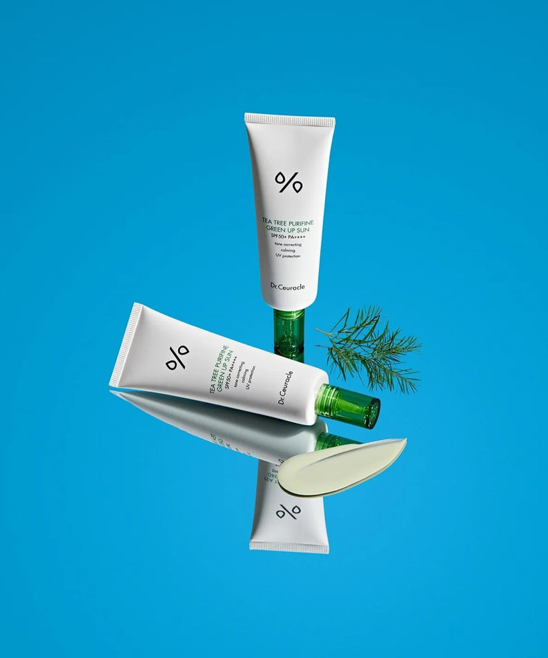 Produit DR.CEURACLE Tea Tree Purifine Green Sup Sun 50ml sur fond bleu avec composants naturels visibles.