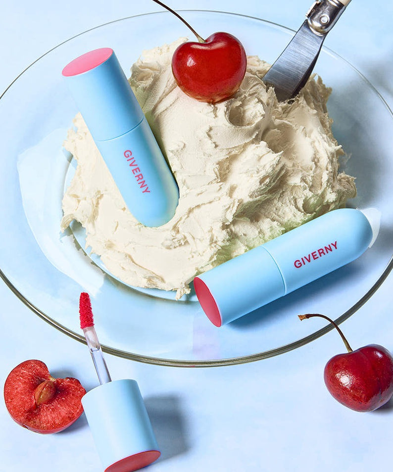 Rouge à lèvres GIVERNY Fluffy Sheer Tint 3.5g sur une assiette avec cerises, mettant en valeur son design élégant et allure délicieuse.
