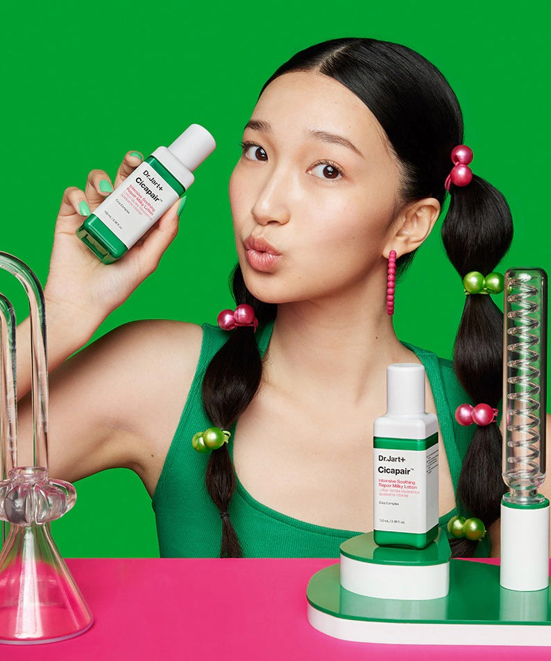 Femme posant avec DR.JART+ Cicapair Intensive Soothing Repair Milky Lotion 100ml devant un fond vert, image promotionnelle.