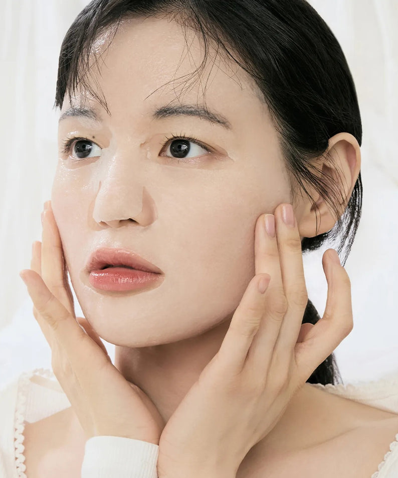 Décris l'image : DR.ALTHEA Cushion Veil Calming Mask (4ea), sur peau apaisée, visage de femme, mains en application.