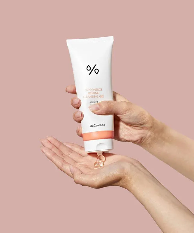 DR.CEURACLE 5 Alpha Control Melting Cleansing Gel 150ml, tube de nettoyage dans une main, fond rose, contexte produit.