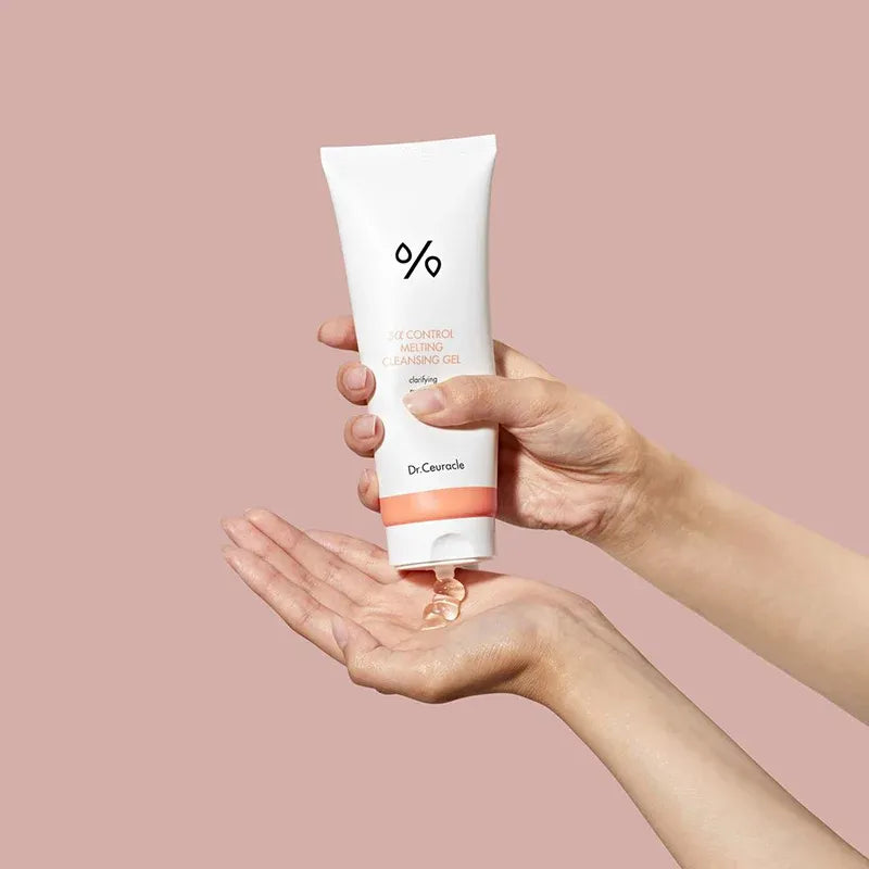 DR.CEURACLE 5 Alpha Control Melting Cleansing Gel 150ml, tube de nettoyage dans une main, fond rose, contexte produit.