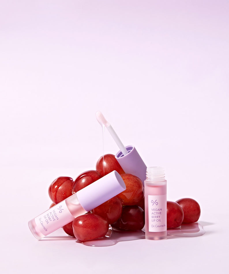 DR.CEURACLE Vegan Active Berry Lip Oil avec des raisins frais en arrière-plan, huile pour lèvres naturelle et nourrissante.