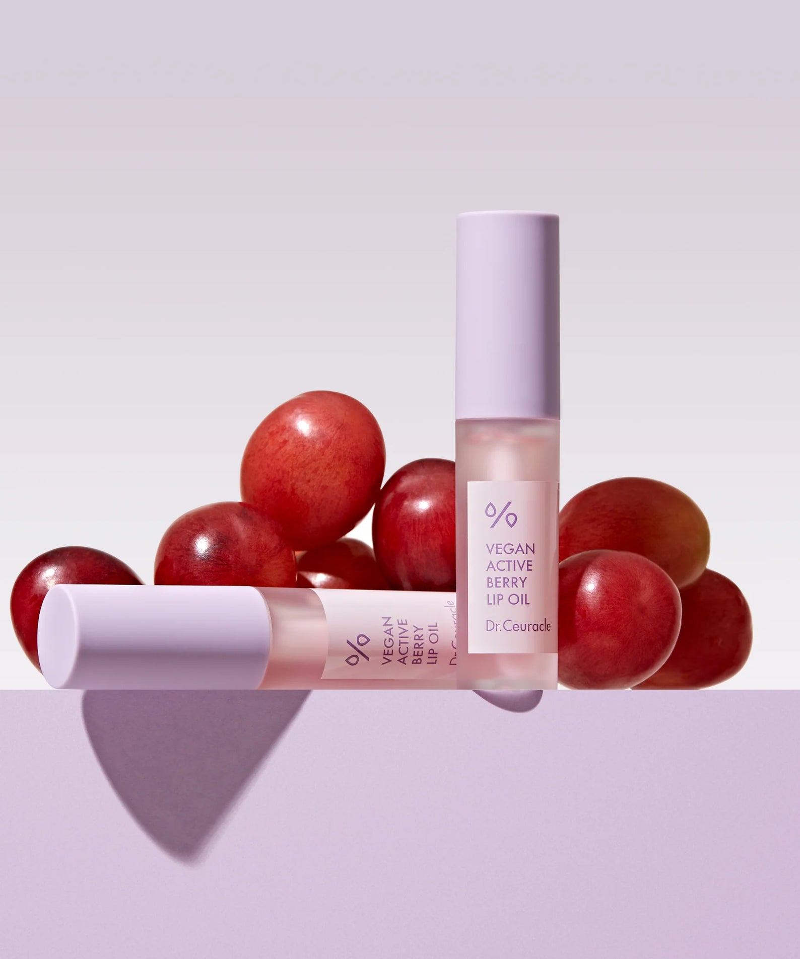 DR.CEURACLE Vegan Active Berry Lip Oil devant des raisins rouges, huile à lèvres hydratante et vegan, produit cosmétique naturel.