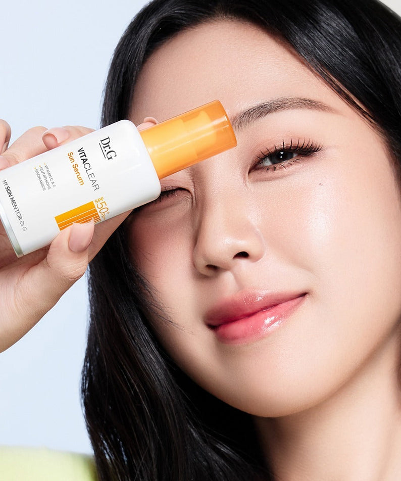 Dr.G Vita Clear Sun Serum 50ml de Dr.G sur peau, sérum solaire appliqué par une femme, flacon blanc et orange.