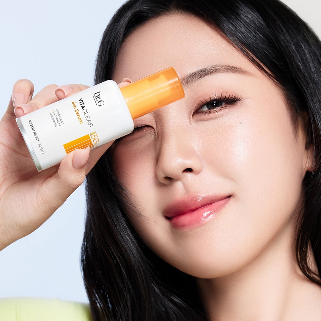 Dr.G Vita Clear Sun Serum 50ml de Dr.G sur peau, sérum solaire appliqué par une femme, flacon blanc et orange.