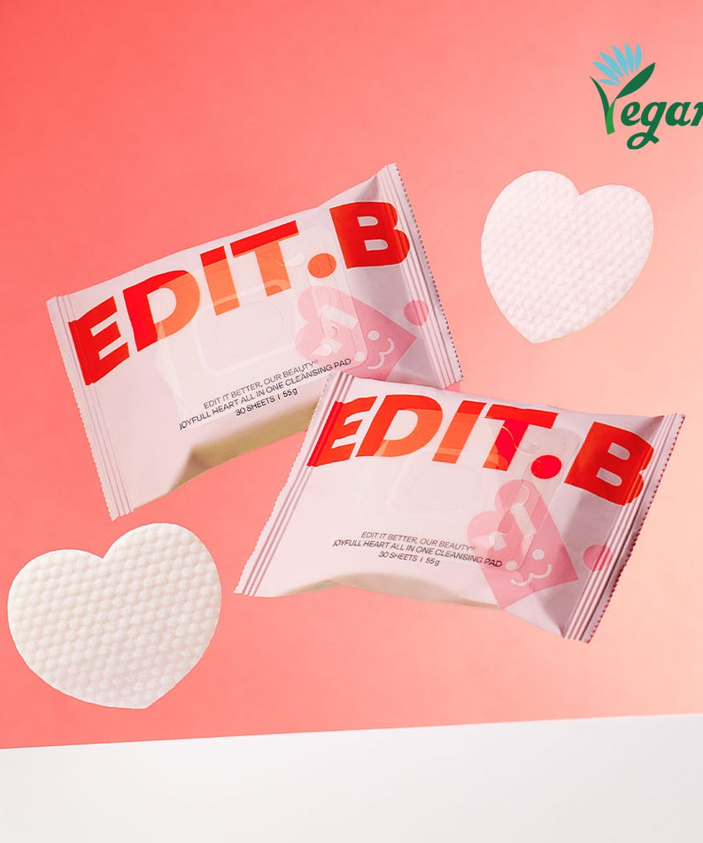 Deux paquets de EDIT.B Joyful Heart All-in-One Cleansin Pad 30 Sheets avec symboles de coeur, certifié vegan sur fond dégradé rose.