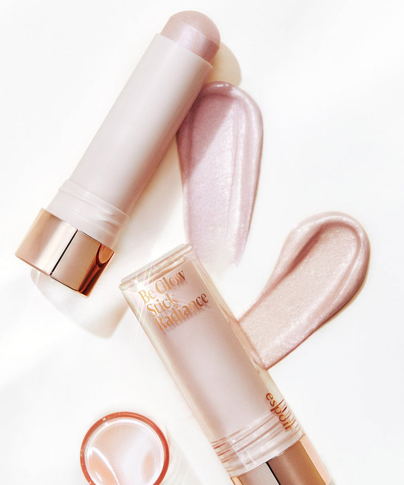 ESPOIR BE GLOW STICK RADIANCE, illuminateur en stick avec reflets subtils, lumière rosé sur fond blanc. Cosmétique éclat effet naturel.