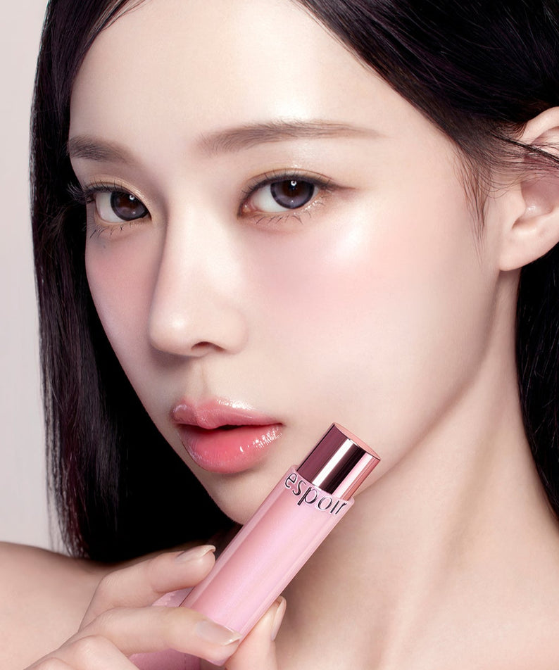 ESPOIR Bare Glow Lip Balm, la marque sur un baume lèvres rose, gros plan maquillage sur visage, fond clair.
