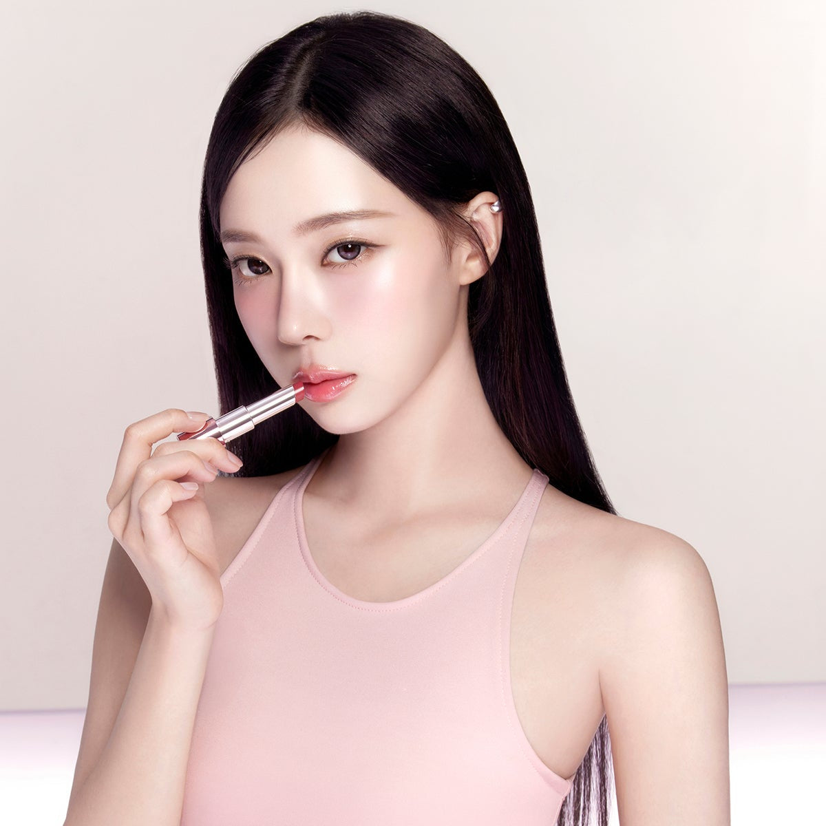 Décris l'image en français : ESPOIR Bare Glow Lip Balm de la marque, appliqué sur des lèvres, modèle en studio fond clair.
