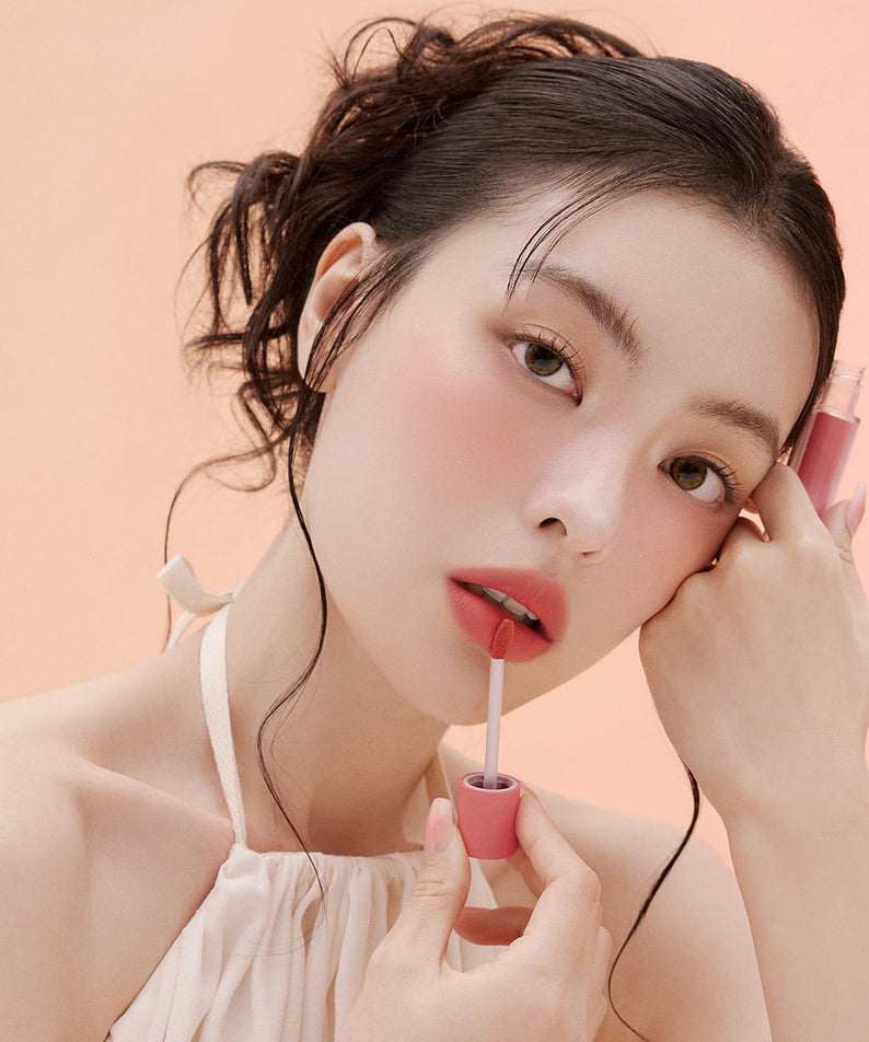 Femme appliquant ESPOIR Couture Lip Tint Fitting Blur pour une finition éclatante et floue. Maquillage lèvres élégant et moderne.