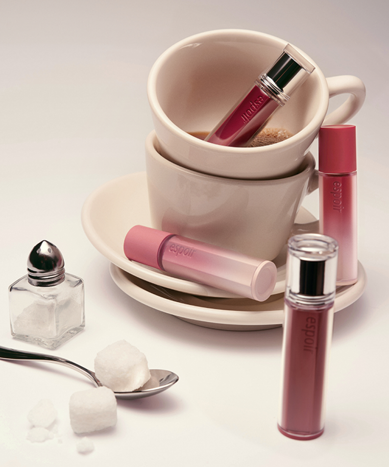 ESPOIR Couture Lip Tint Glaze [NEW COLOR] en rose, flacon et embout sur tasse et cuillère, décor maquillage.