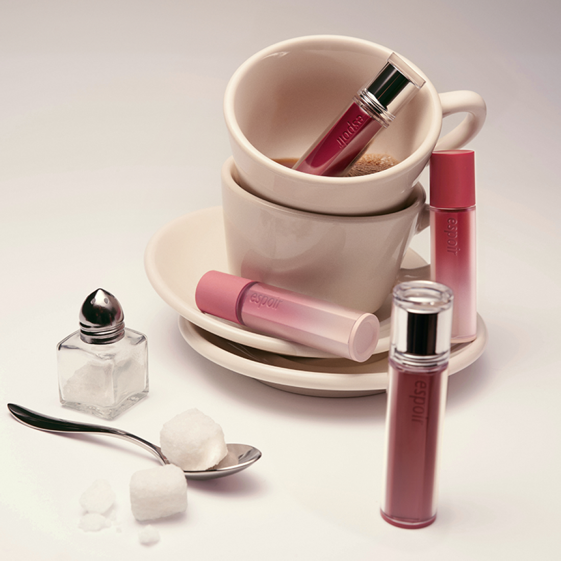 ESPOIR Couture Lip Tint Glaze [NEW COLOR] en rose, flacon et embout sur tasse et cuillère, décor maquillage.