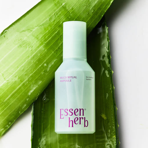 ESSENHERB Mucoritual Ampoule 120ml, flacon sur feuille d’aloe verte, photo produit marque ESSENHERB en contexte skincare