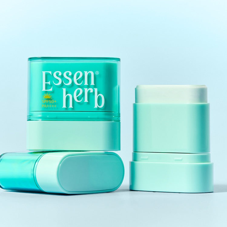 ESSENHERB  Multi Defense Cloud Fit Airy Sun Stick 10g, stick solaire vert, sur fond clair bleu, pack produit en studio.