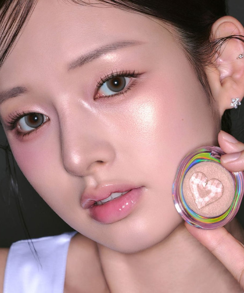 ETUDE Shooting Beam Highlighter 3g de la marque ETUDE, sur peau maquillée; visage en gros plan tenant le produit.