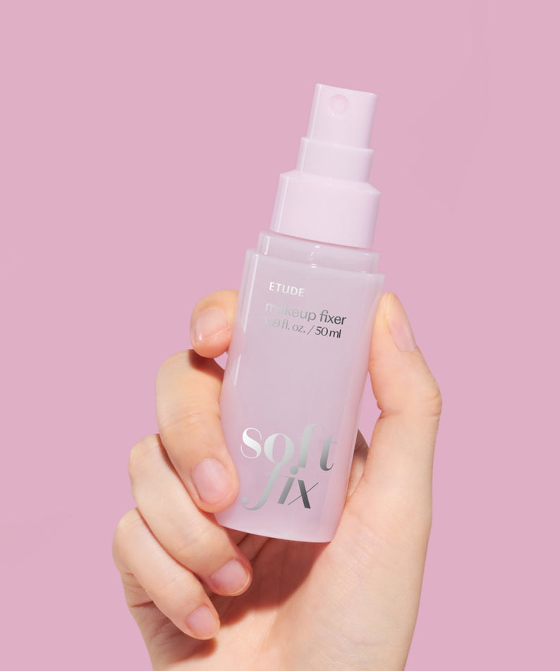 ETUDE  Soft Fix Makeup Fixer 50ml, main tenant le spray cosmétique sur fond rose pastel (marque ETUDE).