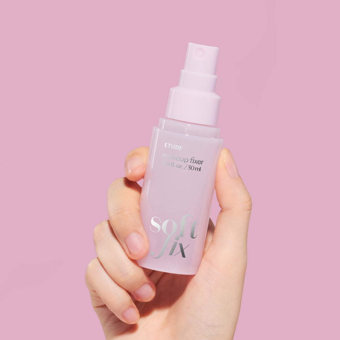 ETUDE  Soft Fix Makeup Fixer 50ml, main tenant le spray cosmétique sur fond rose pastel (marque ETUDE).