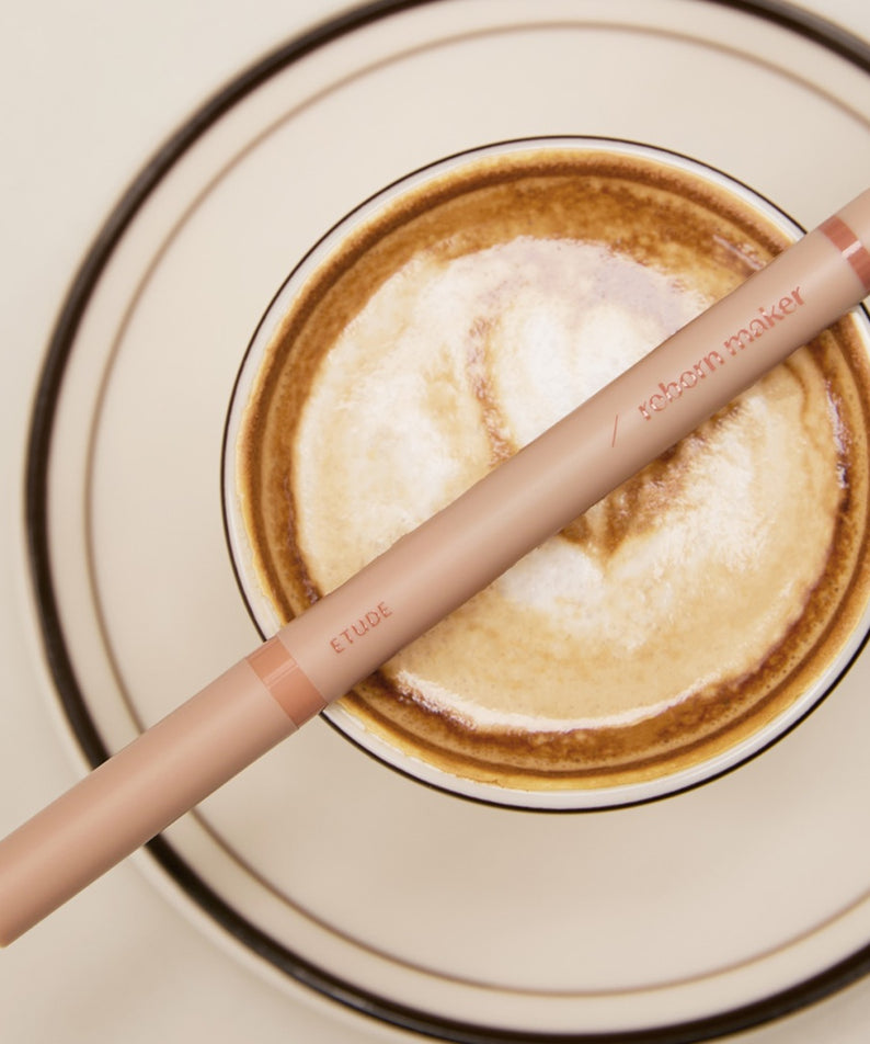 ETUDE Re-creation Maker Aegyo-sal Liner posé sur une tasse de café, produit cosmétique innovant pour un look naturel.