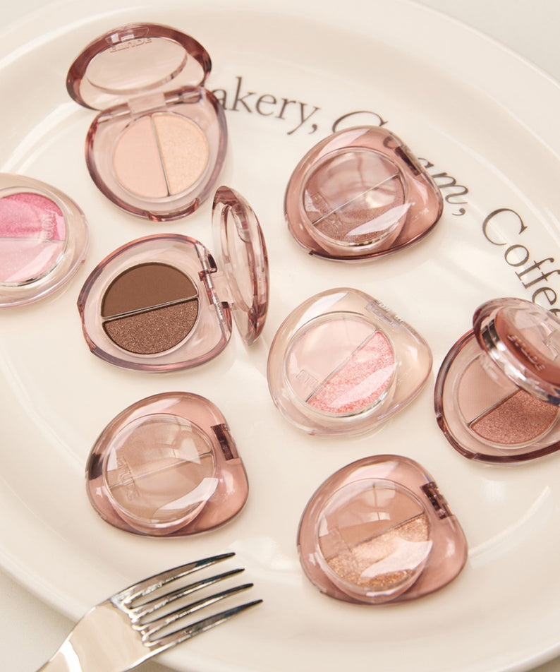 Palette de maquillage ETUDE What's in My Eyes Cafe Double avec fards à paupières en tons pastel et neutres sur une assiette blanche.