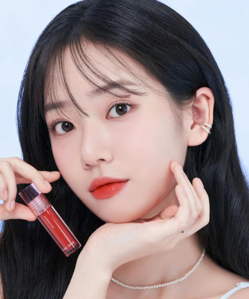 Femme portant le FORENCOS Renewal Tattoo Tint, couleur vive sur lèvres, fond bleu clair.