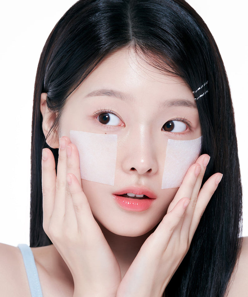 Jeune femme appliquant des patchs pour le visage avec une expression surprise.