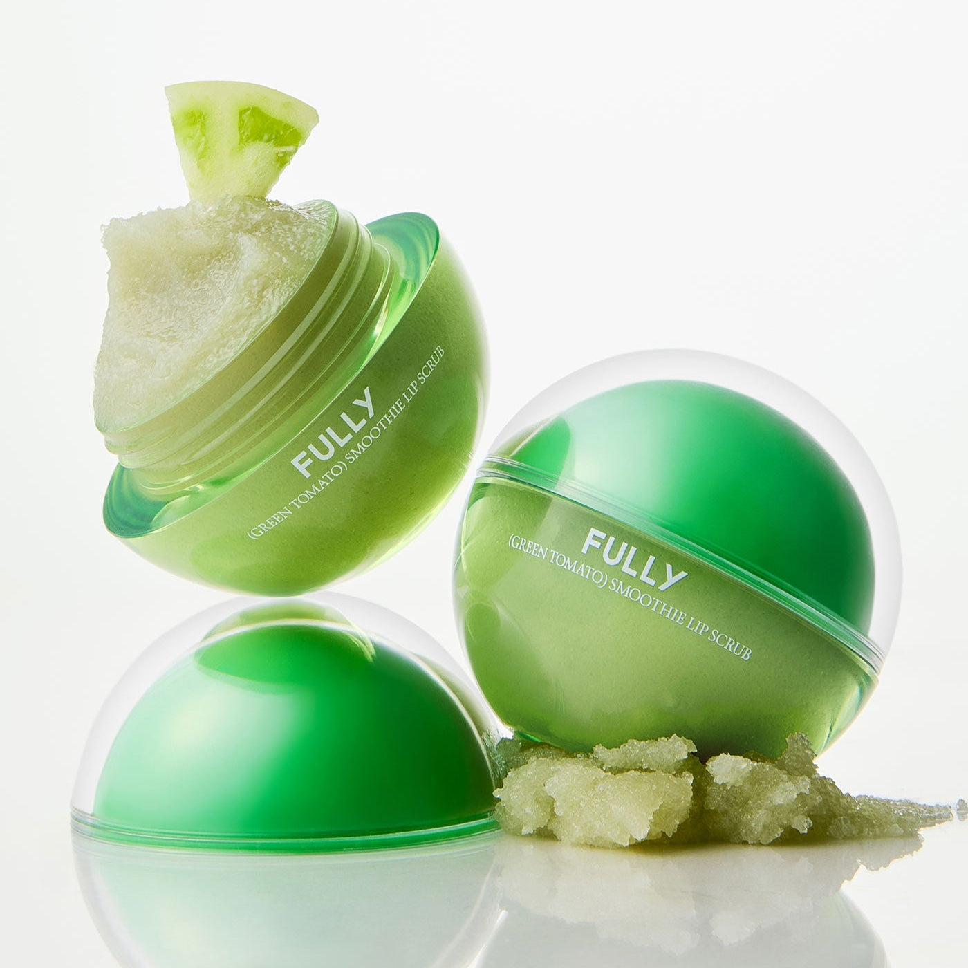 Décris l'image en français : FULLY Green Tomato Smoothie Lip Scrub 12g, marque FULLY, pot vert sur fond blanc.