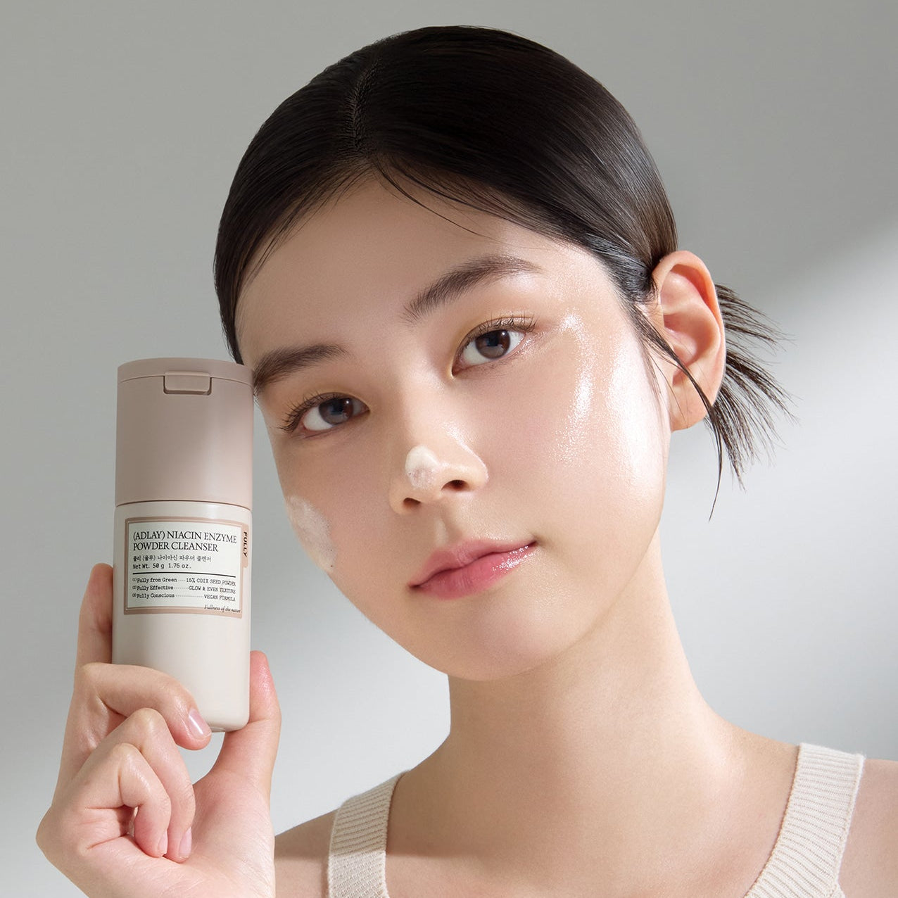 FULLY Yulmu Niacin Enzyme Powder Cleanser 50g de FULLY, flacon tenu par une femme, fond clair, soin visage