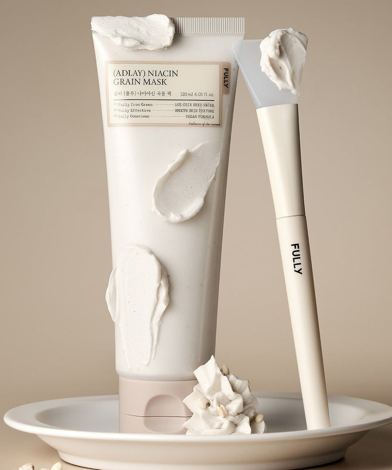 Crème FULLY Job's tears niacin grain pack 120ml avec applicateur blanc sur une assiette, produit pour soin de peau.