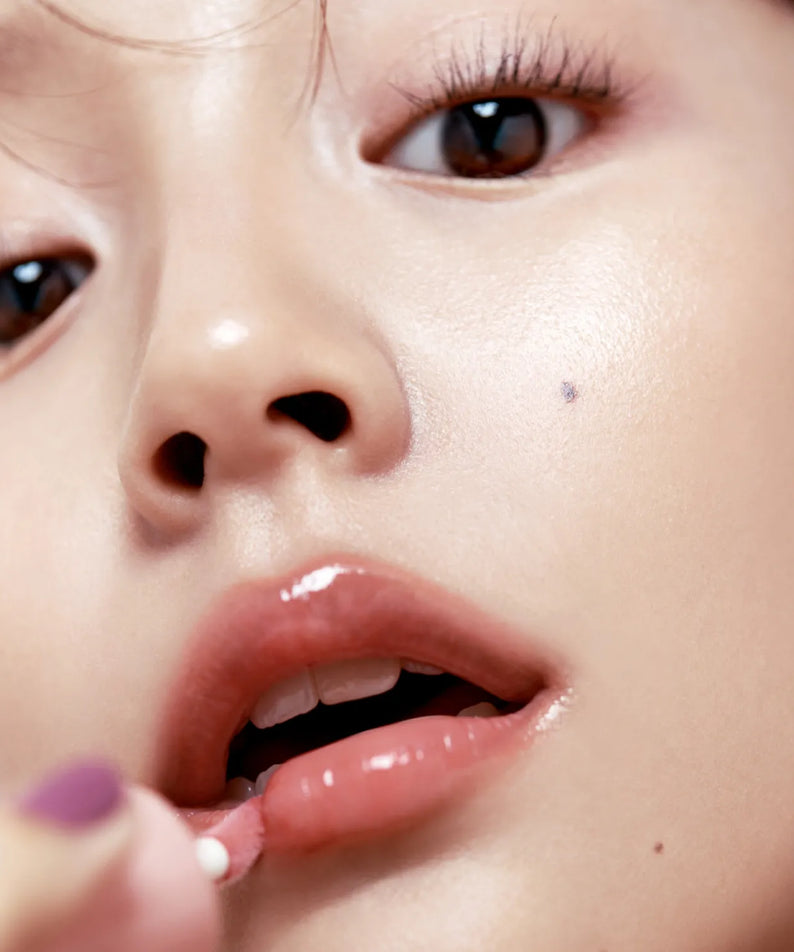 Application de FWEE 3D Voluming Gloss sur les lèvres pour un effet volumisant et brillant.