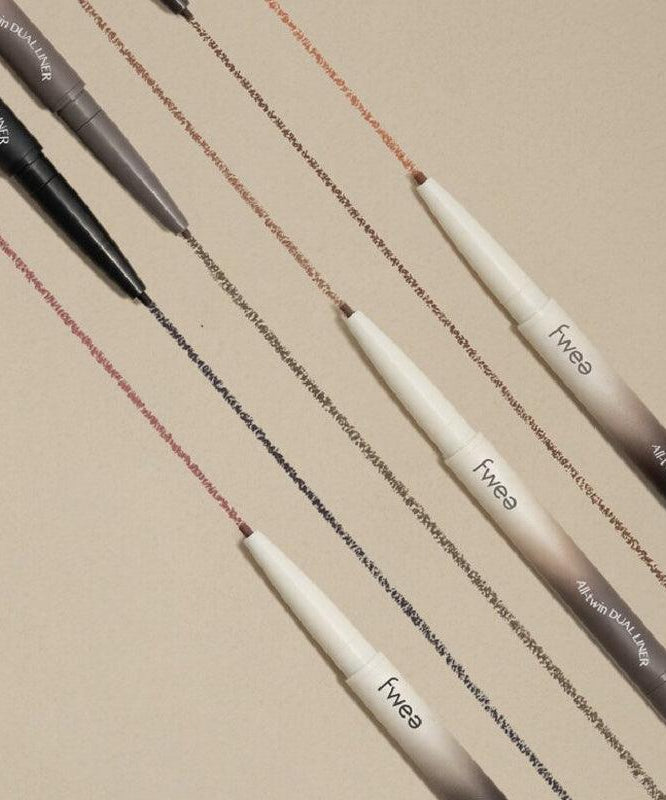 Crayons FWEE Oltime Dual Liner disposés sur une surface beige, affichant différentes nuances tracées, maquillage pour les yeux.