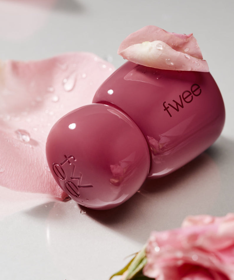FWEE Rose Obsession 18 colors, tube maquillage rose fwee sur fond fleurs, gouttelettes, image produit.