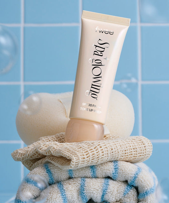 FWEE Spa Glowing UV Tone-Up Base 35ml 2 Types, tube FWEE sur serviettes et fond bleu spa, visuel produit