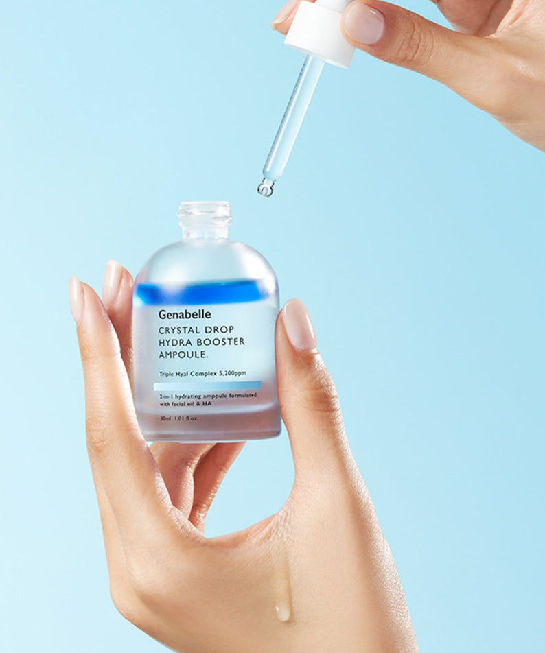GENABELLE Crystal Drop Hydra Booster Ampoule 30ml par Genabelle : main verseur d’ampoule goutte, fond bleu clair, soin hydratant.