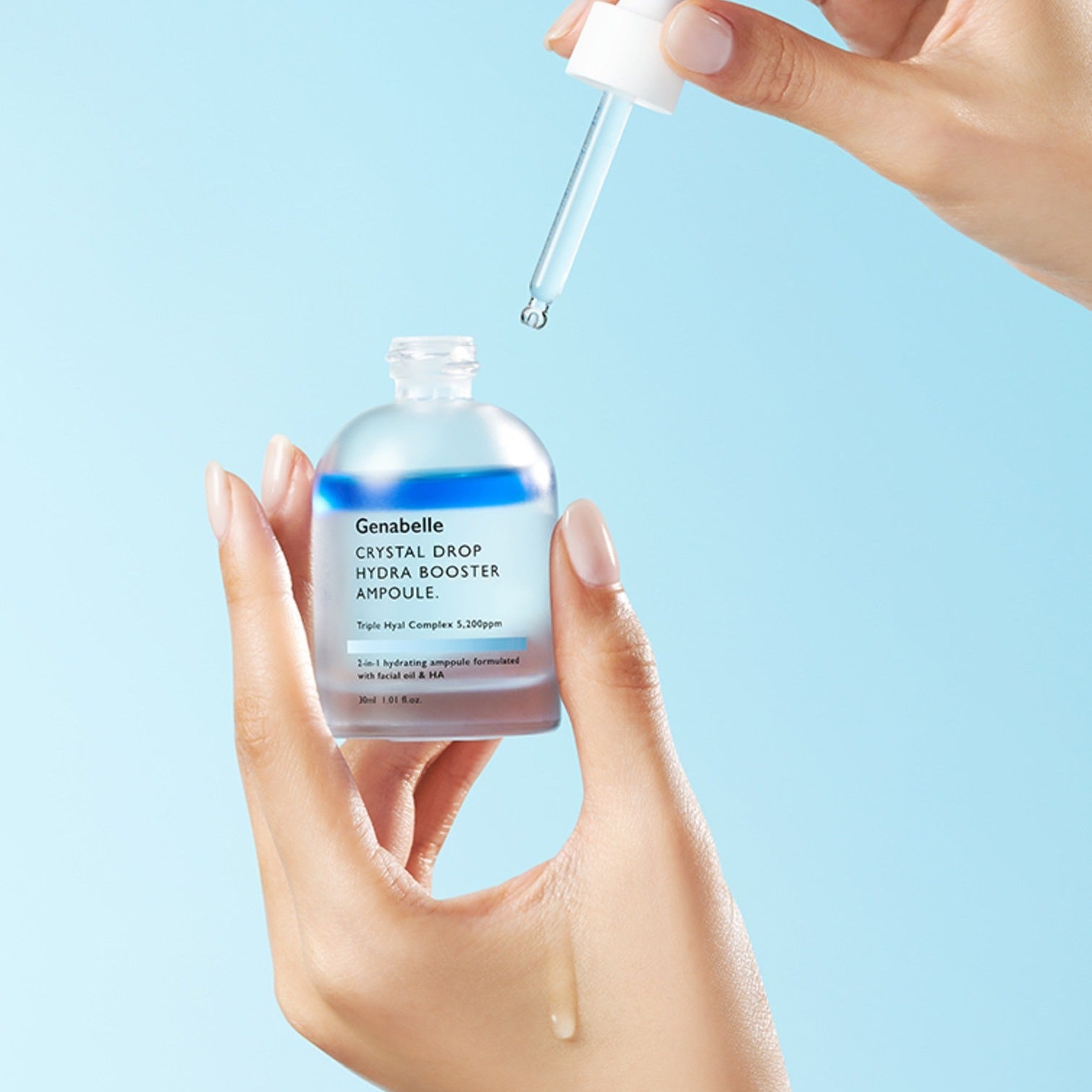 GENABELLE Crystal Drop Hydra Booster Ampoule 30ml par Genabelle : main verseur d’ampoule goutte, fond bleu clair, soin hydratant.