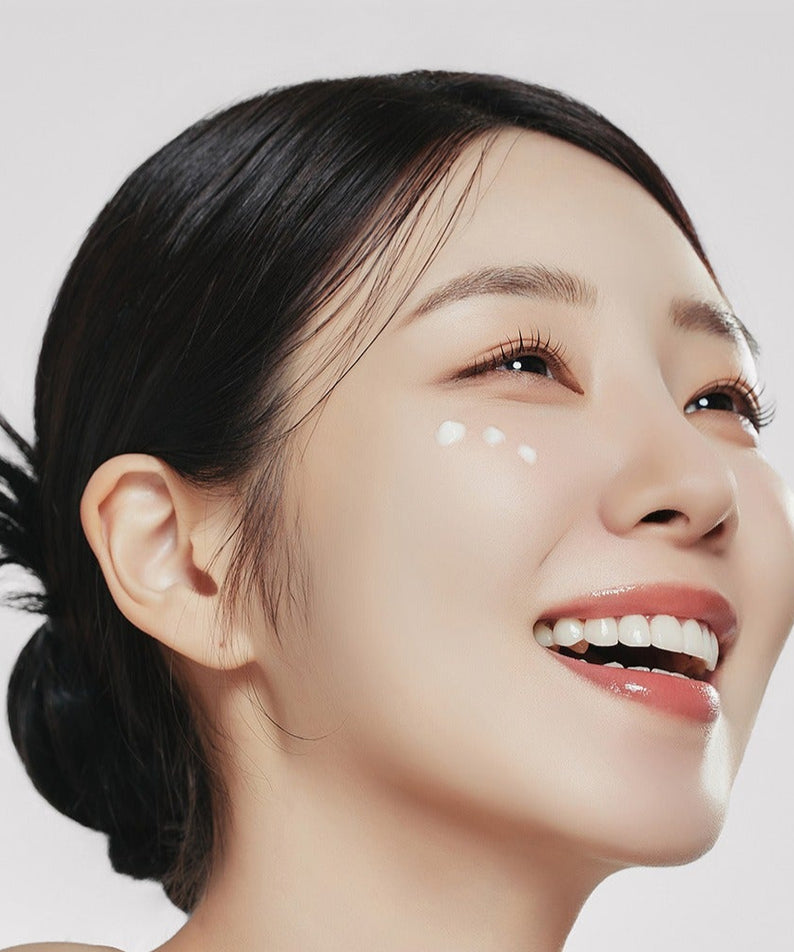 Femme souriante appliquant GENABELLE PDRN Enriched Recovery Balm 50ml pour une peau lumineuse et hydratée.