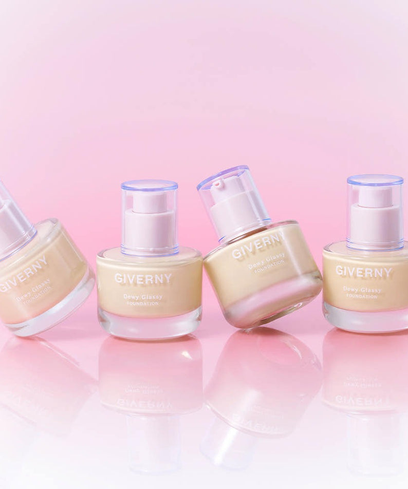 Décris l'image en français: GIVERNY Dewy Glassy Foundation 30ml (SPF38, PA++), flacons sur fond rose pastel.