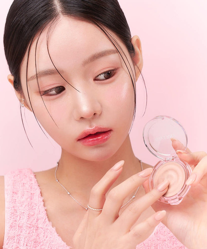 GIVERNY Dewy Voluming Highlighter 3g de la marque GIVERNY, femme applique un enlumineur lumineux en gros plan, fond rose.