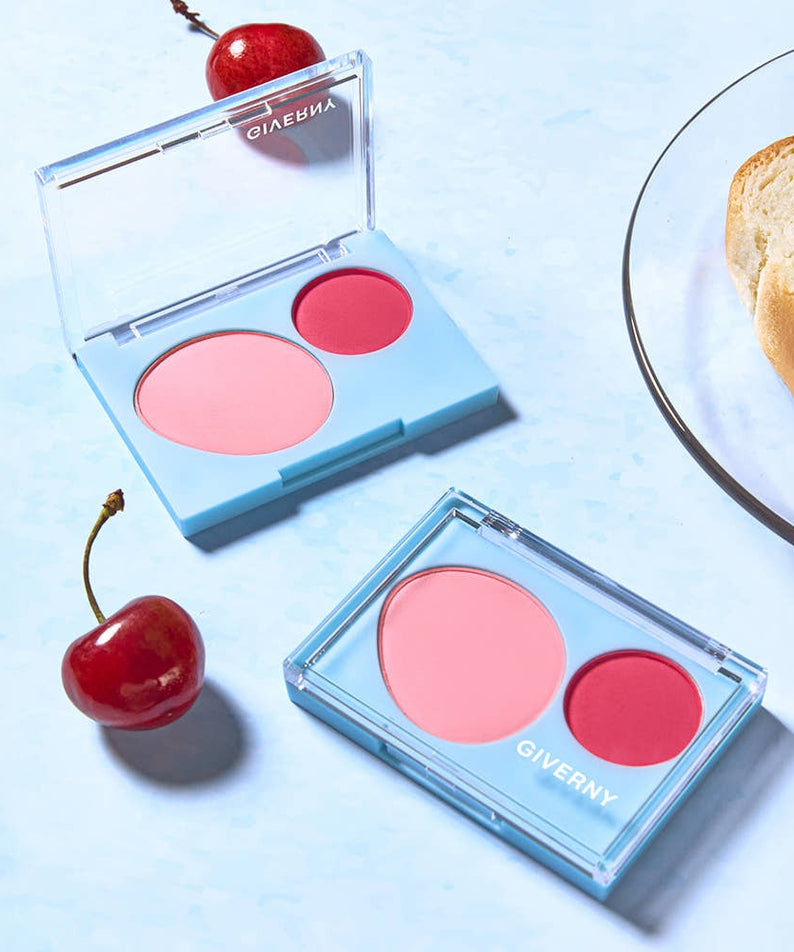 Deux blushers GIVERNY Fluffy Dual Blusher 7.4g ouverts sur une table avec des cerises et du pain.