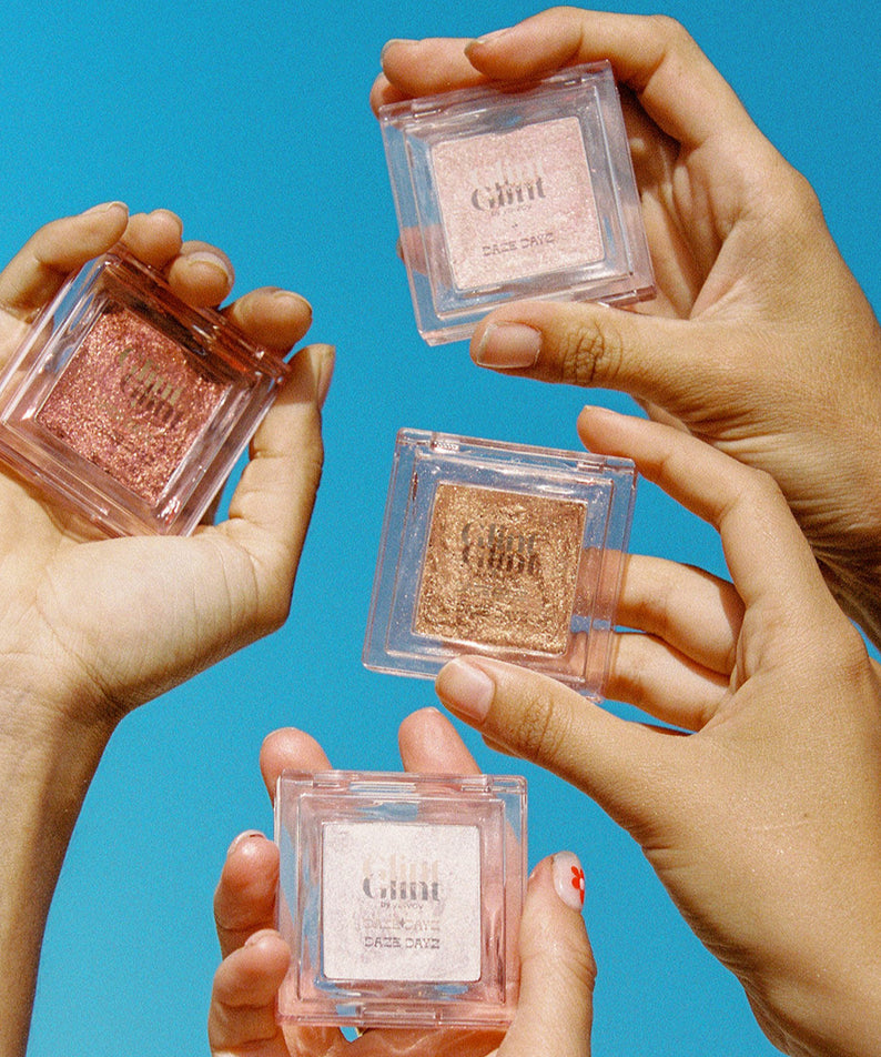 GLINT Glint Highlighter (Marble) présenté par des mains sur un fond bleu vif.