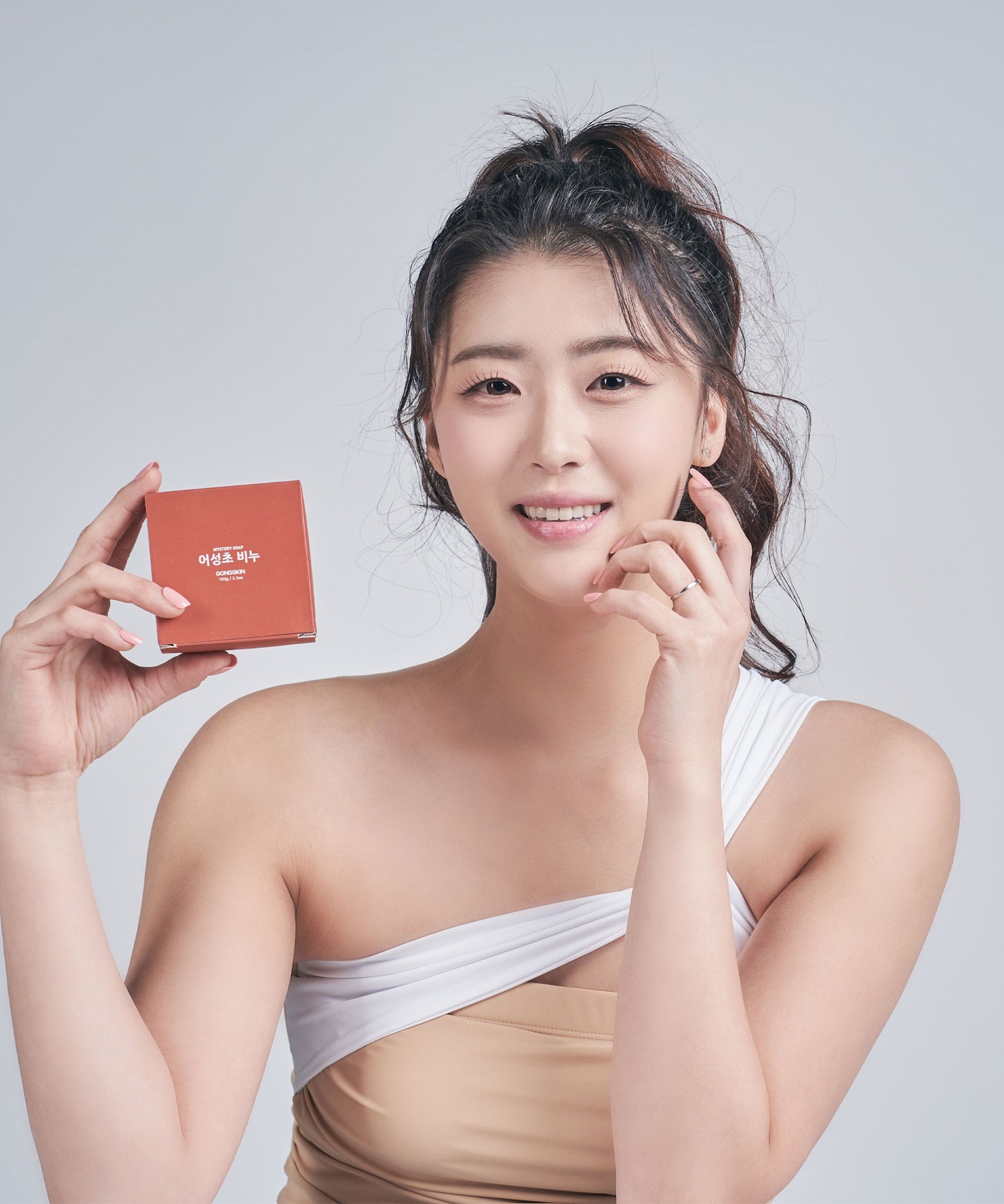 Femme tenant GONGSKIN Eoseongcho Soap 100g avec sourire.