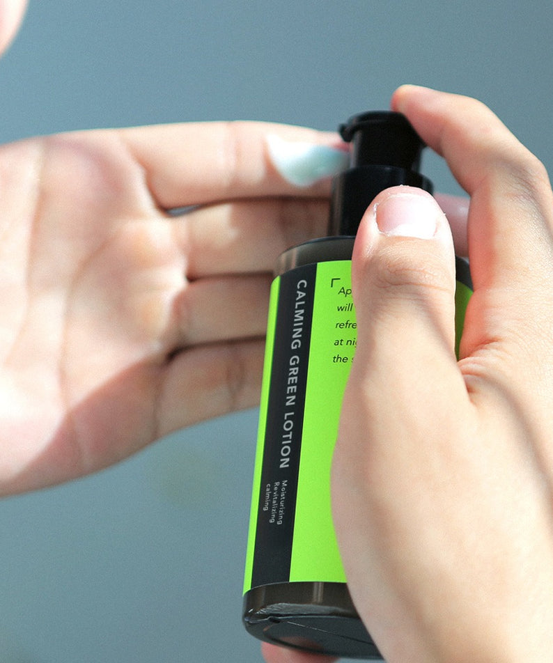 GRAFEN  Calming Green Lotion 160ml : tube vert apaisant tenu en main sur fond bleu, marque GRAFEN en gros plan